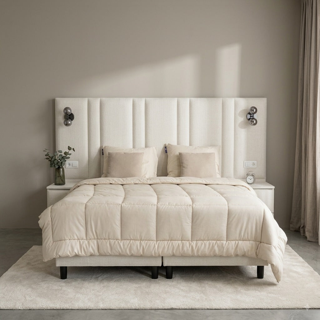 Premium boxspring op maat in creme, vooraanzicht met hoog gestoffeerd wandhoofdbord